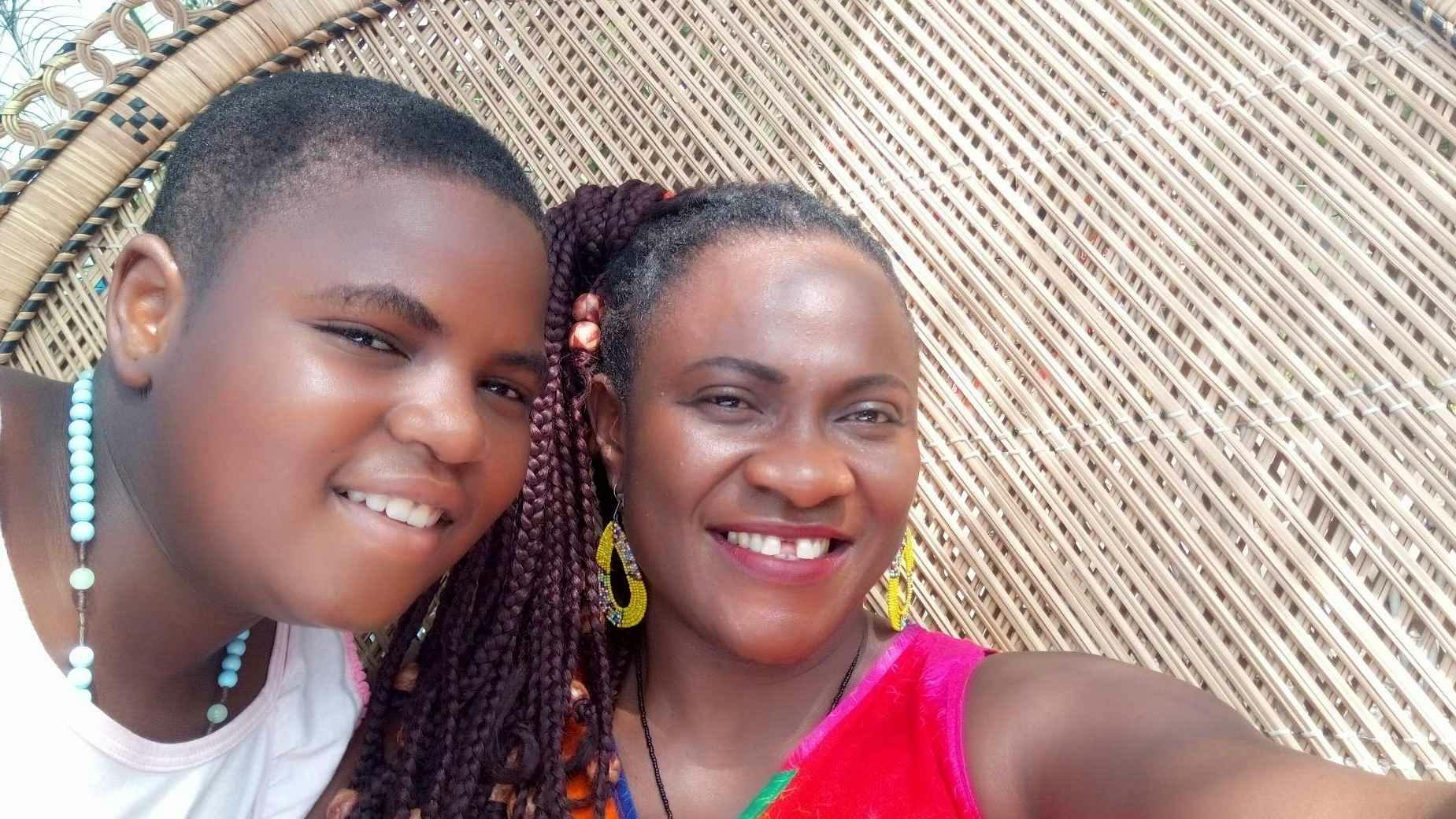 Image depicts a young girl and her mother wearing colorful jewelry and smiling at the camera.